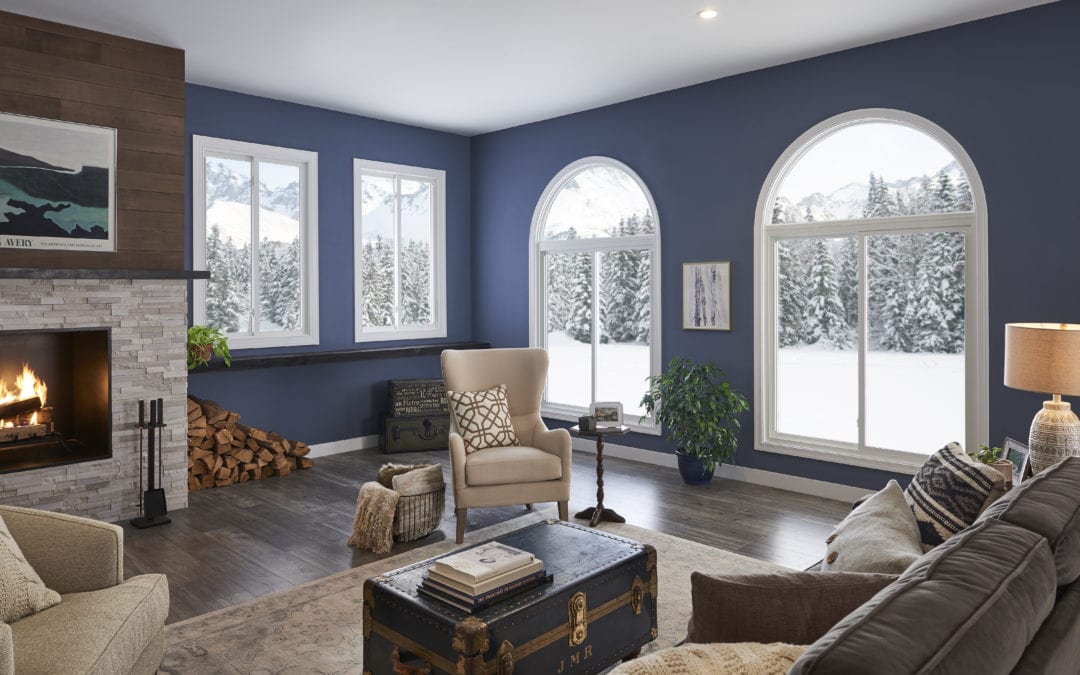 A beautiful living room with blue walls and a fireplace overlooking a snowy landscape.