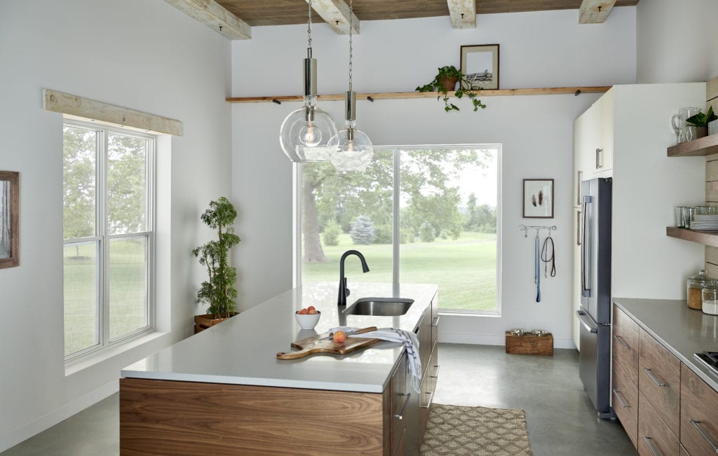 A well-lit kitchen with white walls, wooden cabinets and concrete floors