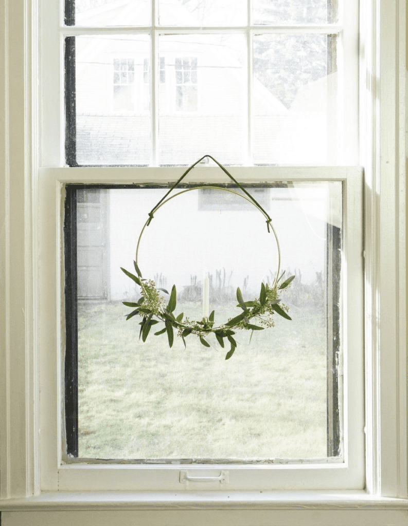 This white-trimmed window has a candle wreath centered on the lower sash.
